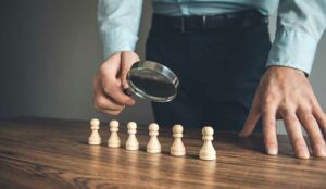 A magnifying glass evaluating six chess pieces