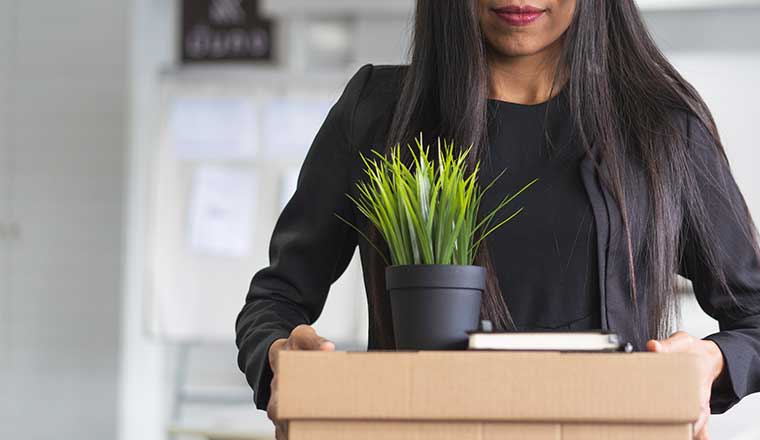 Person holding personal stuff and leaving workplace.