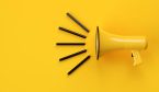 Yellow megaphone or bullhorn with lines over yellow background,