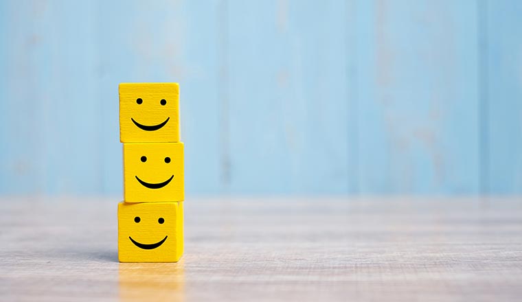 Three stacked smiley face cubes representing customer satisfaction