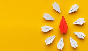 Leadership concept with a Red paper plane surrounded by white ones