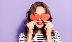 Happy person holding hearts over eyes