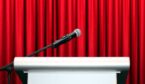 A microphone on stage with red curtain background