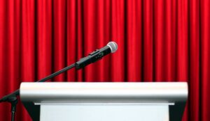 A microphone on stage with red curtain background