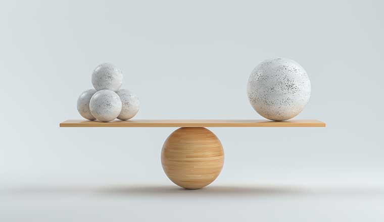 Wooden scale balancing one big ball and four small ones