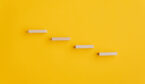 Four blank wooden pegs placed in a stairway like structure