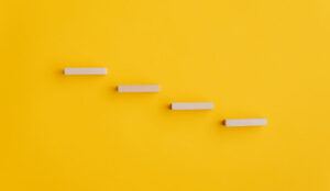 Four blank wooden pegs placed in a stairway like structure