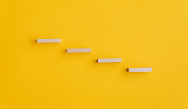 Four blank wooden pegs placed in a stairway like structure