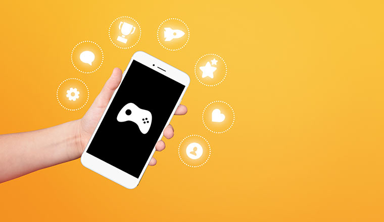 Gamification concept with hand holding smartphone with game icons