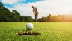 A golf player putting golf ball into hole