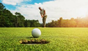 A golf player putting golf ball into hole