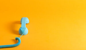 Vintage style blue telephone handset on a yellow background