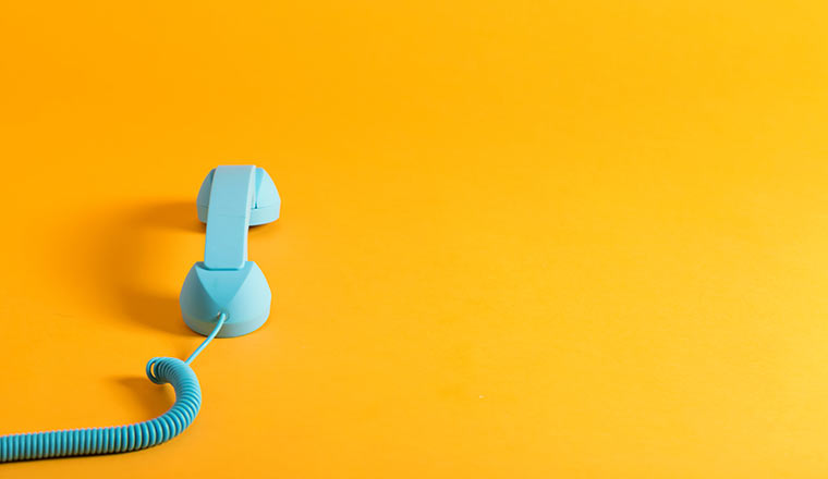 Vintage style blue telephone handset on a yellow background