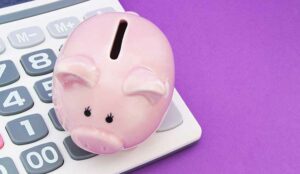 Piggy bank and calculator on purple background