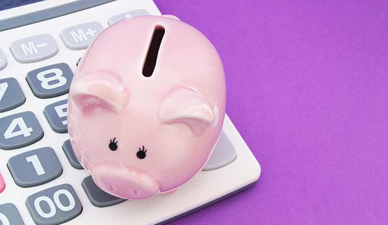 Piggy bank and calculator on purple background