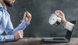 hand holding a clock coming out of laptop screen