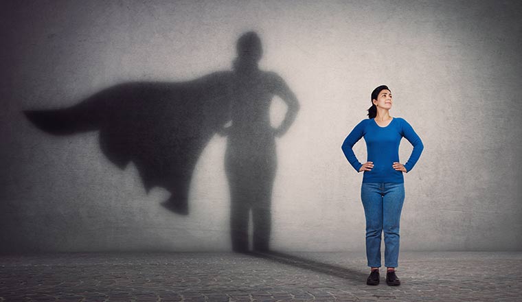 Person casting a superhero with cape shadow on the wall.