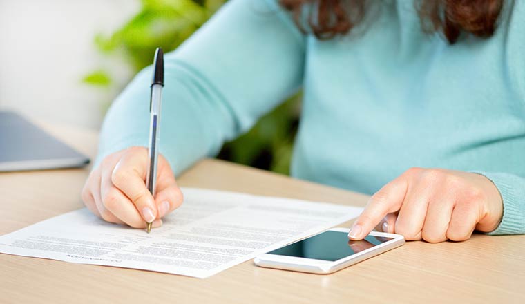 Person writing an using phone