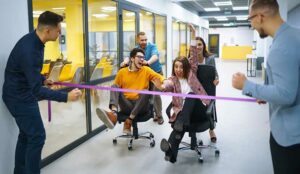 business people having fun while racing on office chairs