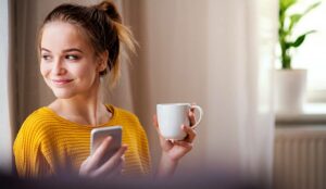 A happy person with a phone and coffee