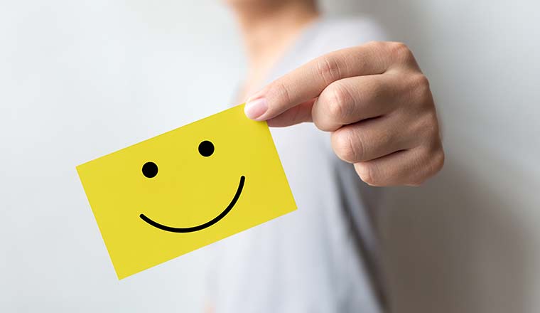 Person holding yellow card with smiley face