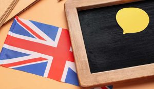 Stationery, chalkboard and UK flag on color background