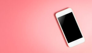 White smartphone and blank screen on pink background
