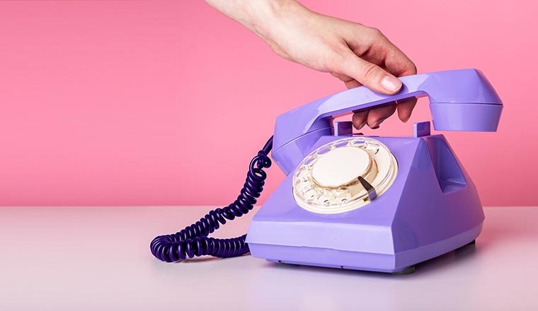 hand holding retro phone handset on pink background