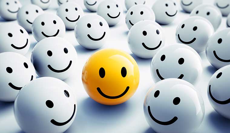 A yellow happy face standing out in crowd of others - customer experience concept