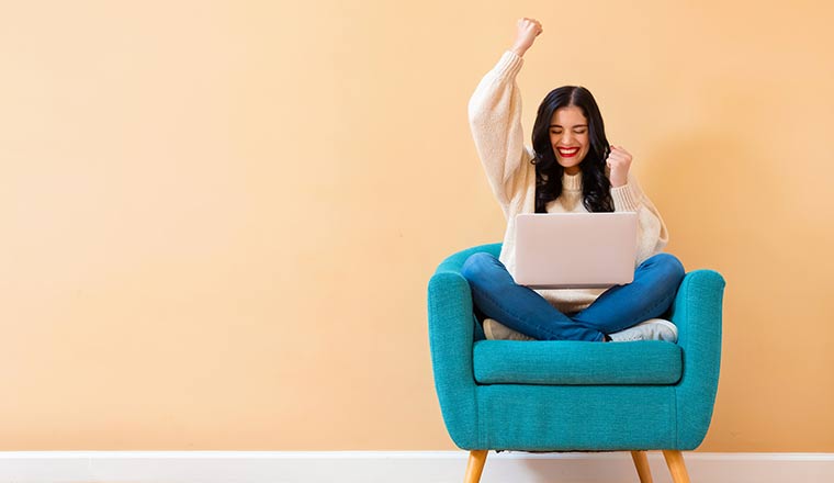 Person celebrating in chair with laptop