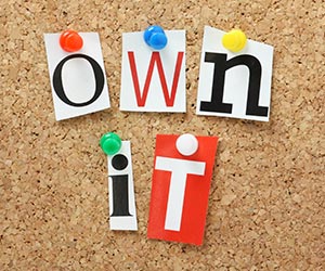 The phrase Own It in magazine letters on a cork notice board