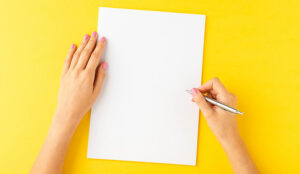 A pair of hands writing on empty white sheet of paper