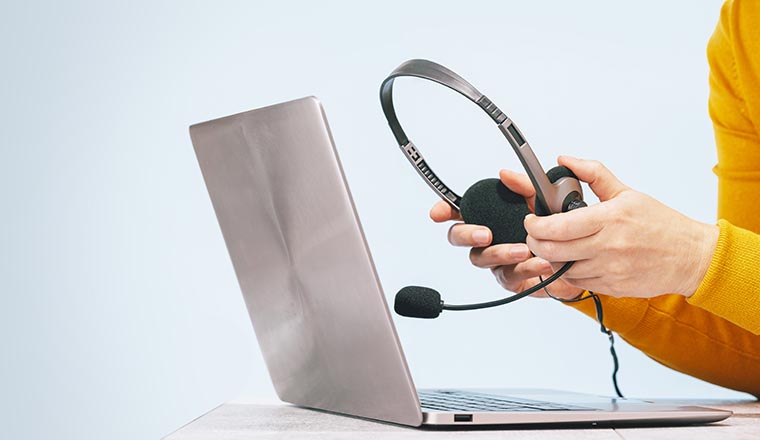 Laptop and headset on desk and plain background.