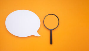Top view of a blank white speech bubble and a magnifying glass