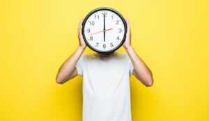 Person holding clock over their face