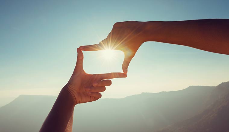 Looking to the future with a close up hand framing looking view sunrise