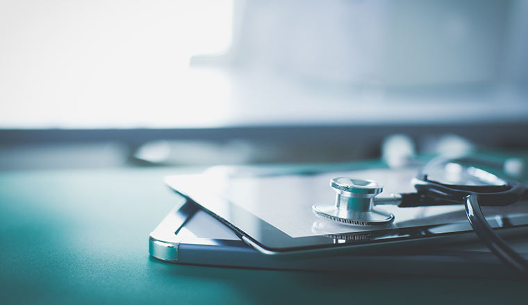 Medical equipment: blue stethoscope and tablet on white background.