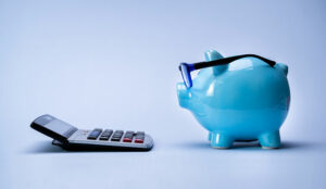 Piggy bank in glasses looking at calculator