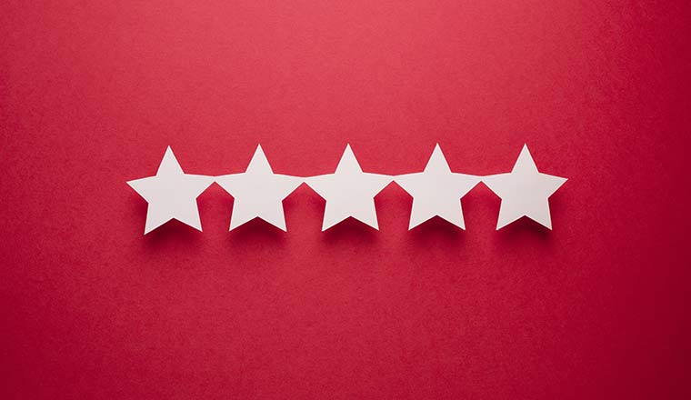 Feedback concept. Five white paper stars of approval on a red background.
