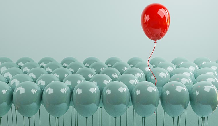 Red balloon floating out from blue balloons that are tied on blue background