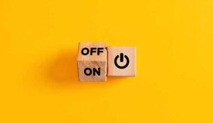 The words on and off on wooden cubes with start icon on yellow background.