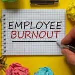 Employee burnout concept, with a hand writing 'Employee burnout' on white note