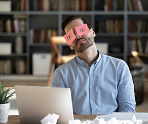 Person sat at desk having given up with post it note eyes