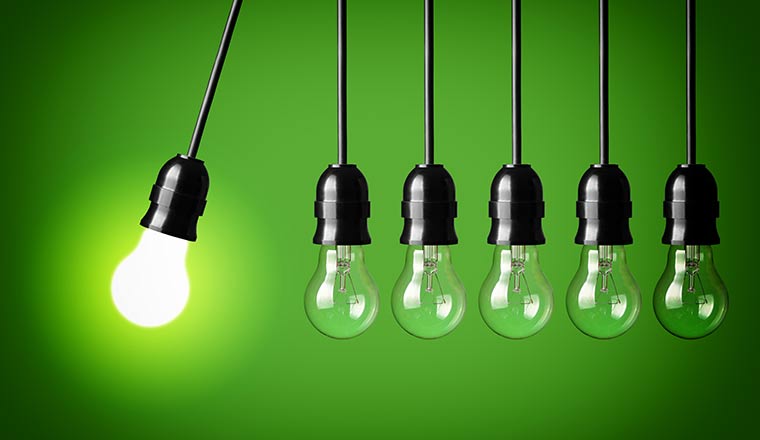 Idea concept on green background. Perpetual motion with light bulbs