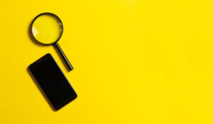 Magnifying glass and smartphone on yellow background
