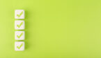Four checkmarks on white cubes against bright green background - testing results concept