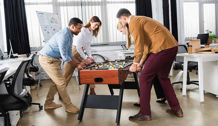 A group of people playing table soccer in office