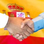 Business handshake on Spain flag background.