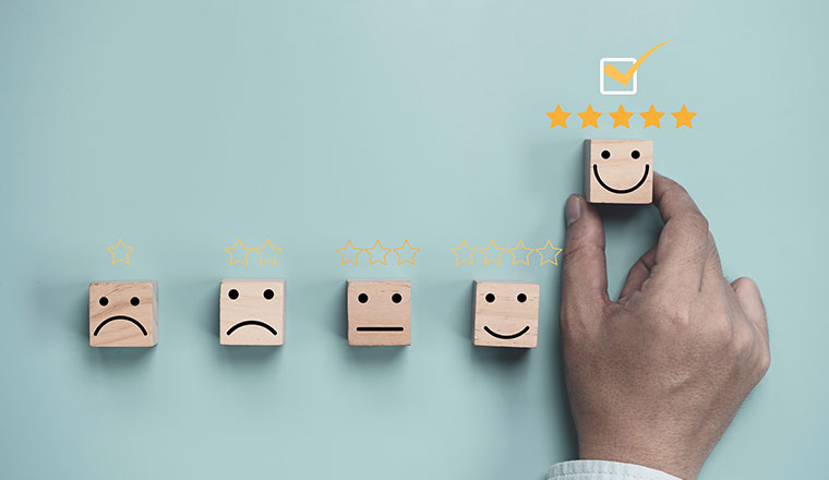 Hand holding and moving up wooden cube block which print screen smiley face with five stars for customer experience