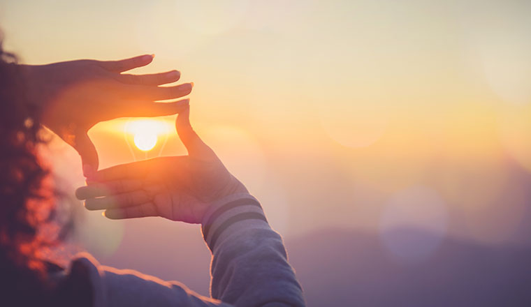 Looking to future concept with person making frame around light with hands